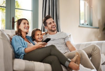 Shot of a happy young family relaxing on the sofa and watching tv together at home.